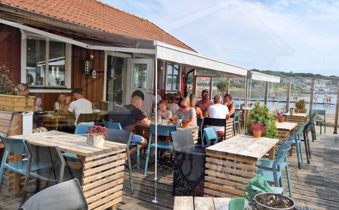 Långa vindstag till terrassmarkis över uteservering vid havet